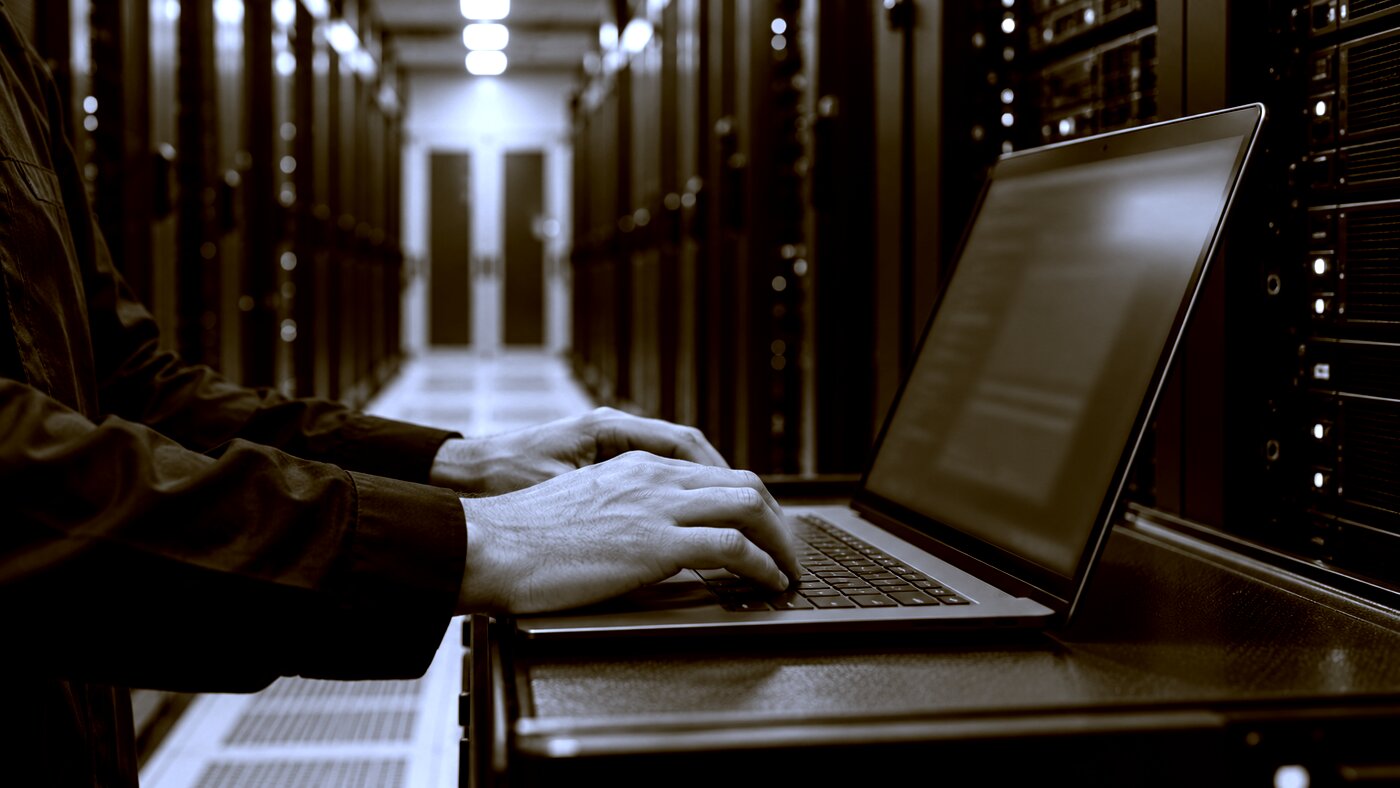 An engineer with a laptop in a data centre aisle